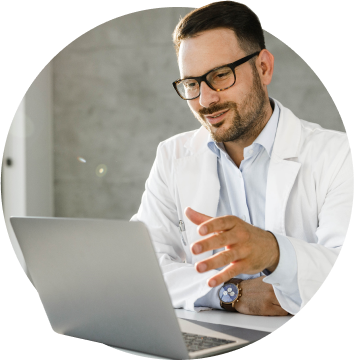 Male doctor wearing glasses having a virtual consultation on a laptop.