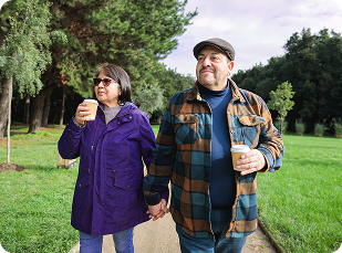 Couple walking holding hands and holding drink cups