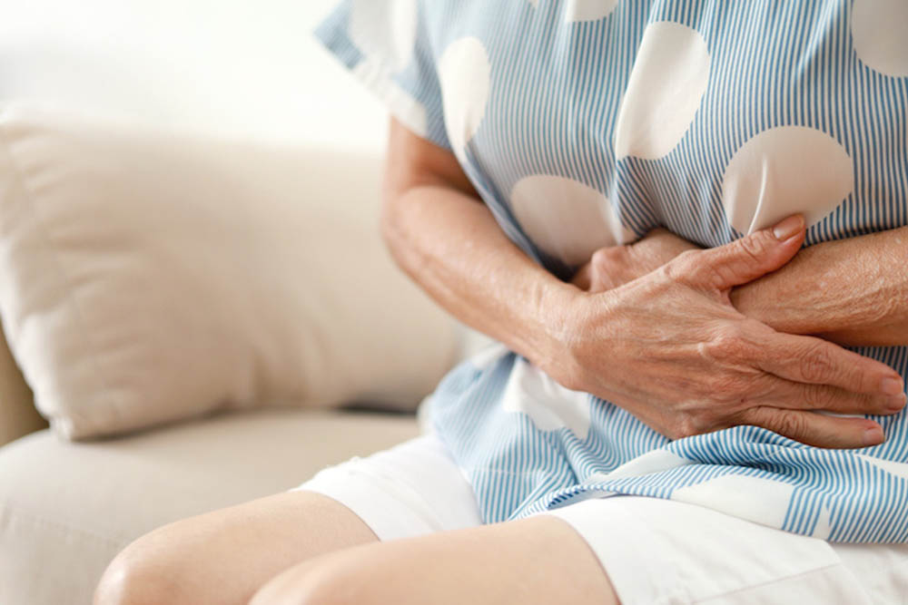 Mujer sosteniéndose el estómago con ambas manos.