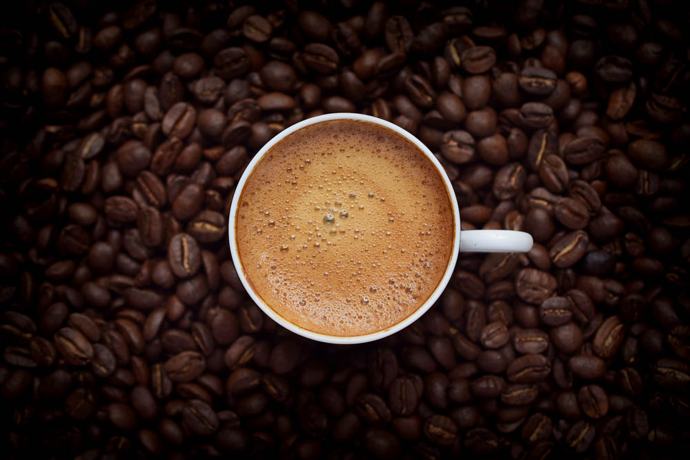 Taza de café con granos de café alrededor.